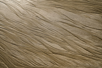 Sand feather patterns created by waves on a beach. 