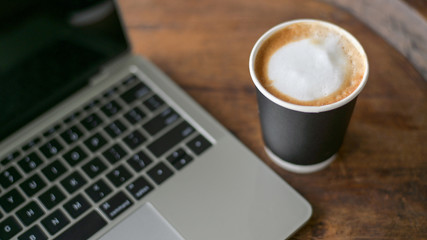 Close-up shot of Take away coffee latte with laptop placed on the table,Top view shot.