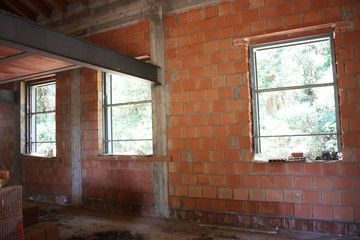 Construction work in an incomplete red brick and concrete house with architectural style details