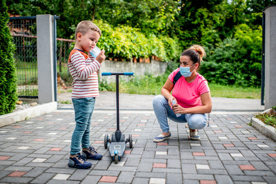 Mother and son with protective masks riding scooter in a front of backyard