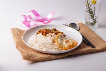 Pork basil with fried egg in a white plate on a white background.