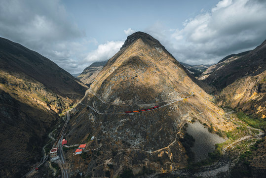 Red train going through the mountain landscape of Chimborazo province, Ecuador