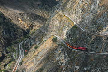 Red train going through the mountain landscape of Chimborazo province, Ecuador