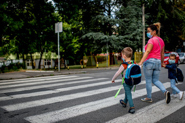 Fototapeta premium Mother and children going to preschool during corona virus. Surgical mask for illness prevention.