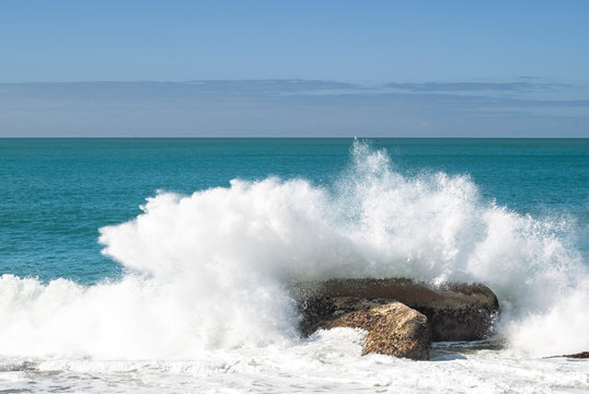 Ocean wave breaking in splash over rock on the beach