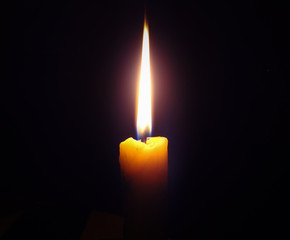 Burning candle  on a dark  black background