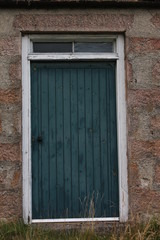 Fototapeta premium weathered wooden green door in stone building