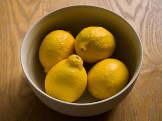 A ceramic bowl with 4 organic yellow lemons. Citrus fruit with vitamin C.