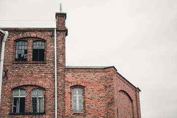 Fachada de ladrillo rojo con ventanas de una pared, paisaje urbano de Polonia. Ruinas urbanas. Fábricas abandonadas.