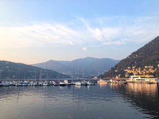 Como Lake, Italy - hills, mountains and water view. Boats and yachts at the marina. Calming autumnal scene, sunset landscape in soft colors