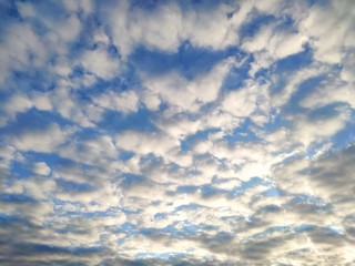 The sun shines on the clouds in the sky. Blue sky with clouds background.
