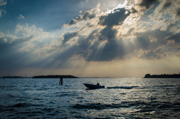Panorama sulla laguna di Venezia al tramonto con un motoscafo che corre veloce sull’acqua 