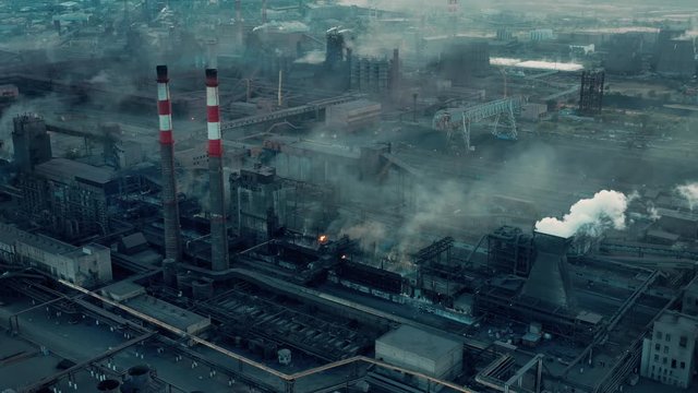 Drone aerial shot factory tubes and chimneys. Fly over zoom in industrial zone, grey and foggy sky, health risk area. Environmental problems, fossil fuels