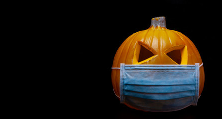 halloween in the age of coronavirus - pumpkin with face mask on black background