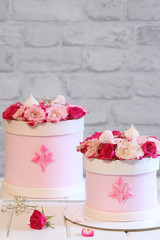 Wedding Flower  Box Cake, covered with light pink fondant and decorated with pink roses, on a light grey brick wall and white wooden table.