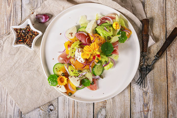 Top view salad with mangoes, vegetables, sweet red onions, mozzarella cheese and capers. Restaurant recipe. Cooking at home delicious