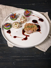 Meat with puffed rice on a white plate on a dark background. Dish of author's cuisine. Turkey meat recipe from a restaurant. Vertical shot