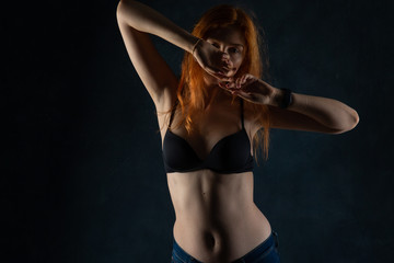 Red-haired model posing in lingerie in a studio environment
