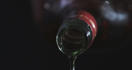 In front of a black background, whiskey is poured into a glass of whiskey stones.
