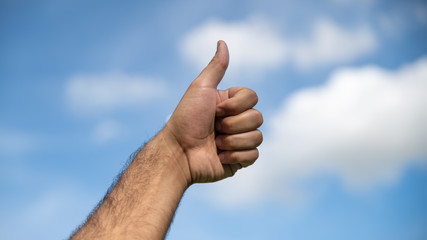 
Thumbs up in the blue sky with cotton clouds