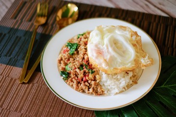 Close-up of Thai basil minced pork with fried egg top on rice and the plate.