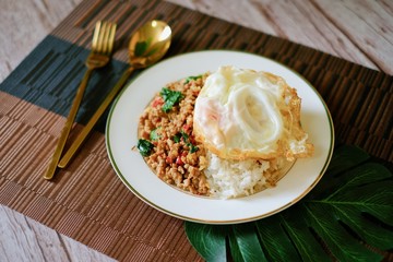 Close-up of Thai basil minced pork with fried egg top on rice and the plate.