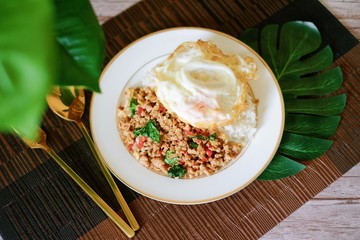 Close-up of Thai basil minced pork with fried egg top on rice and the plate.