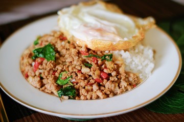 Close-up of Thai basil minced pork with fried egg top on rice and the plate.
