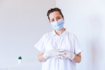 Female doctor in white uniform and protective mask in pose on hospital interior. Medicare. Health care.