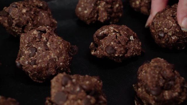 Placing chocolate oatmeal cookie dough ball on pan, Closeup Pan Right