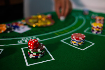 man hand hold Casino equipment placed on the green floor for risky gambling for the people who want to get rich.