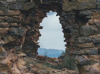 Agujero en muro de piedra antiguo y abandonado con vistas a paisaje de montaña