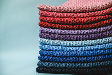 Stack of knitted material from multicolored threads on a blue background. Copy, empty space for text