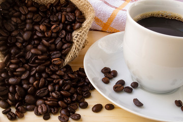 Cup of espresso with bag of spilled coffee beans