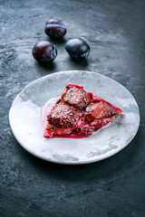 Modern style French tarte aux prunes with sweet plums and vanilla offered as closeu-up on a design plate copy space