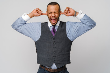 Young african american man holding his hands up to his ears trying to mute all the voices he hears and screaming