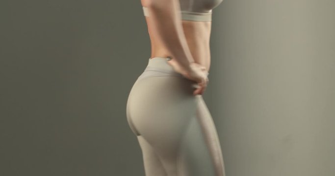 Close-up of fit and muscular women body, sportswoman bottom and abs. Female athlete in leggings turning backwards, showing buttocks, strong glutes and thighs, workout and gym excercises progress