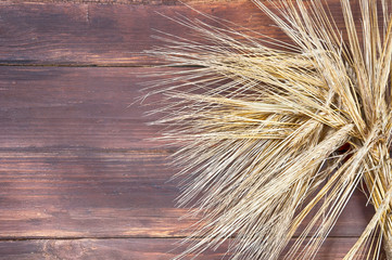 ripe wheat ears in a bundle on a textured wooden table made of planks top view