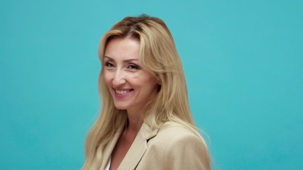 Closeup portrait of funny positive adult blond woman in business jacket fooling around making fish lips and comical face, having fun. Indoor studio shot isolated on blue background