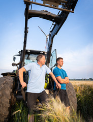 Agrarpolitik und Getreidemarkt - Landwirt und sein Sohn stehen sorgenerfüllt vor einem Traktor im...