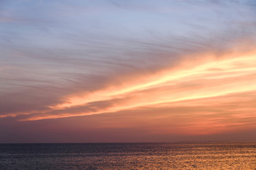 Brilliant orange-red clouds reflected into the ocean in a beautiful sunset