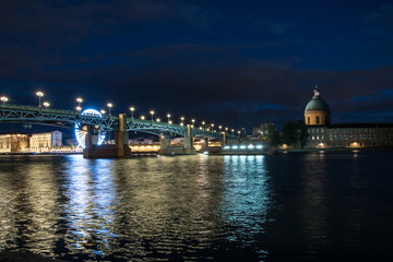 Fototapeta na wymiar Belle vue sur un pont illuminé enjambant un fleuve en ville de nuit 