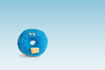 Blue donut with eyes and biscuit against blue background