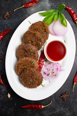 Many beef or chicken cutlet, tomato sauce Kerala South India. hot and spicy tea time snack on white plate, dark black background. fried meat of veal, mutton or fish. Top view Indian snack non veg food