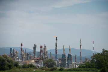 Obraz premium panorama of chemical factory with orange flame on stormy sky background