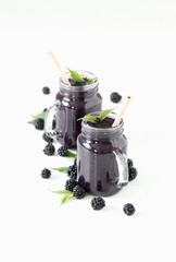 BlackBerry smoothie in a glass jar with bamboo straw on a white background