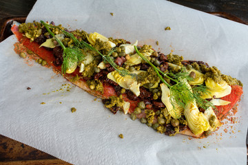 Mediterranean Salmon in Parchment Paper: Raw salmon fillet topped with artichoke hearts, sun-dried tomatoes, capers, kalamata olives, pesto sauce, and fresh dill