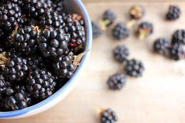 Bowl of fresh blackberries on wooden background. Top view. Summer berries on the table

