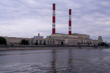 a factory on the river embankment with large striped pipes