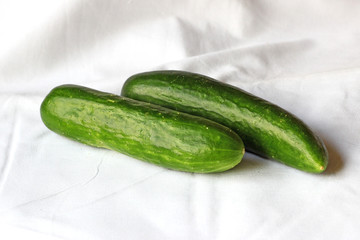 Close up of two cucumbers on white fabric